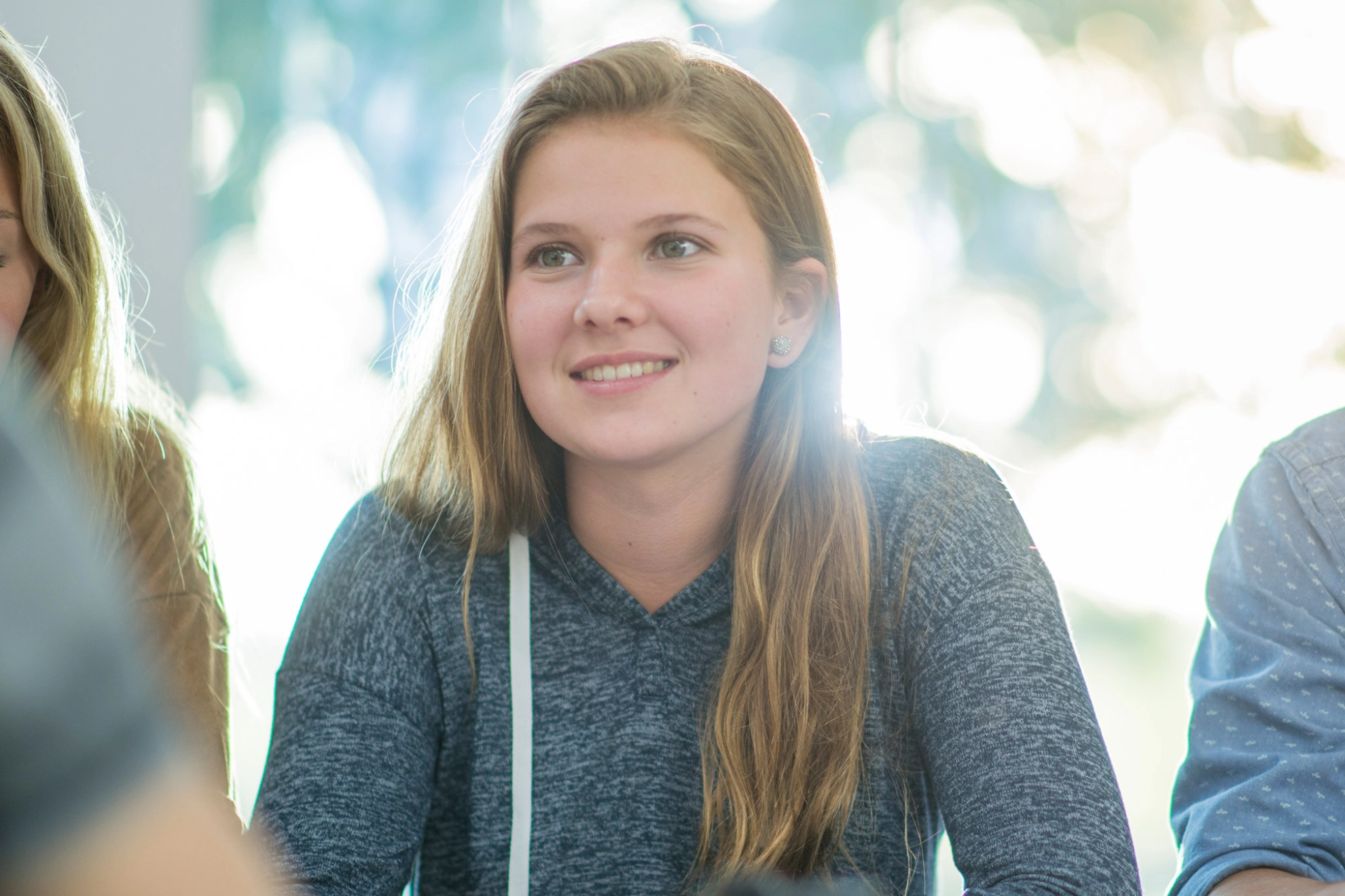 Ein Blondes Mädchen schaut lächelnd nach vorne während eines Seminars.